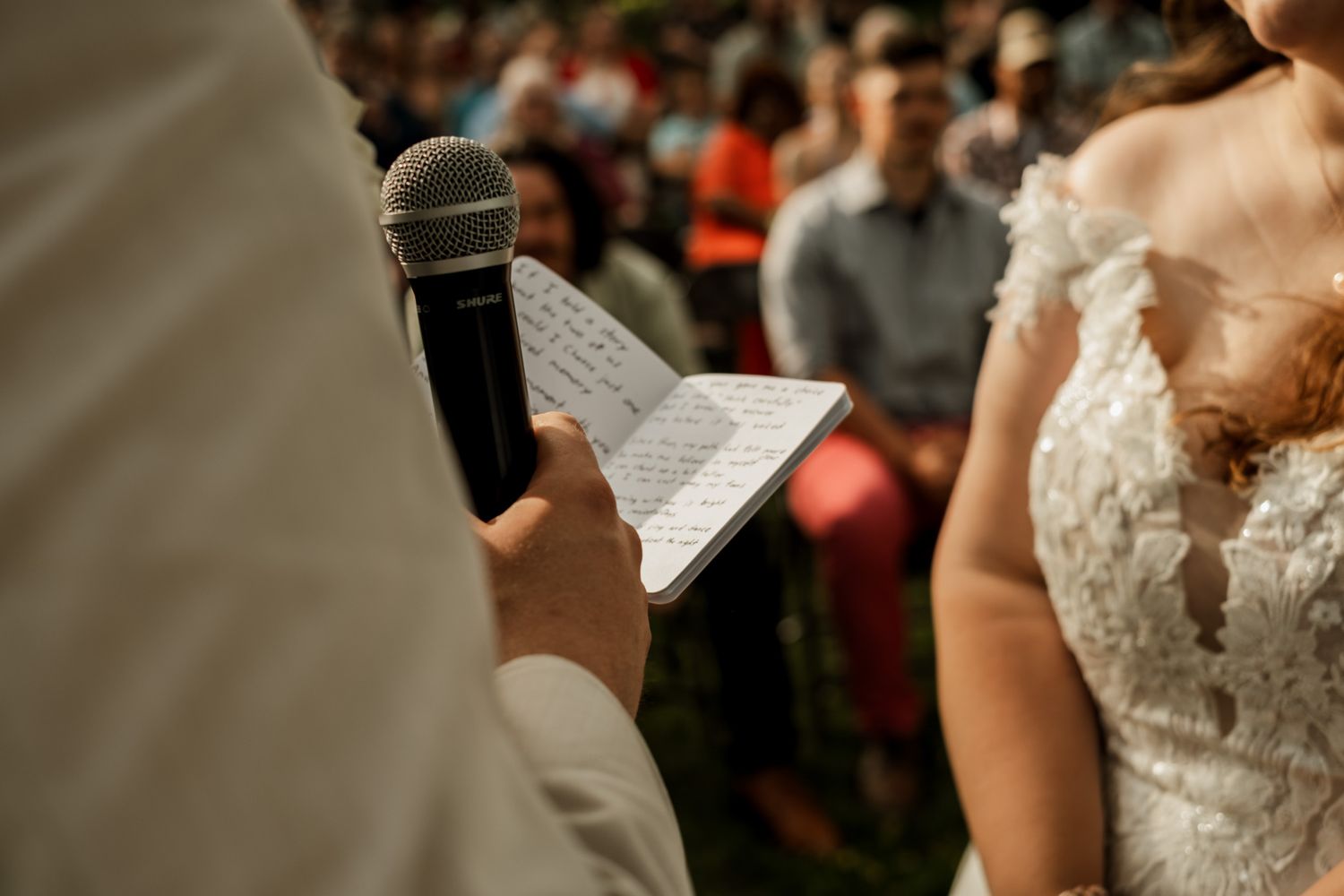 Wedding ceremony guests watching as vows are exchanged outdoors.