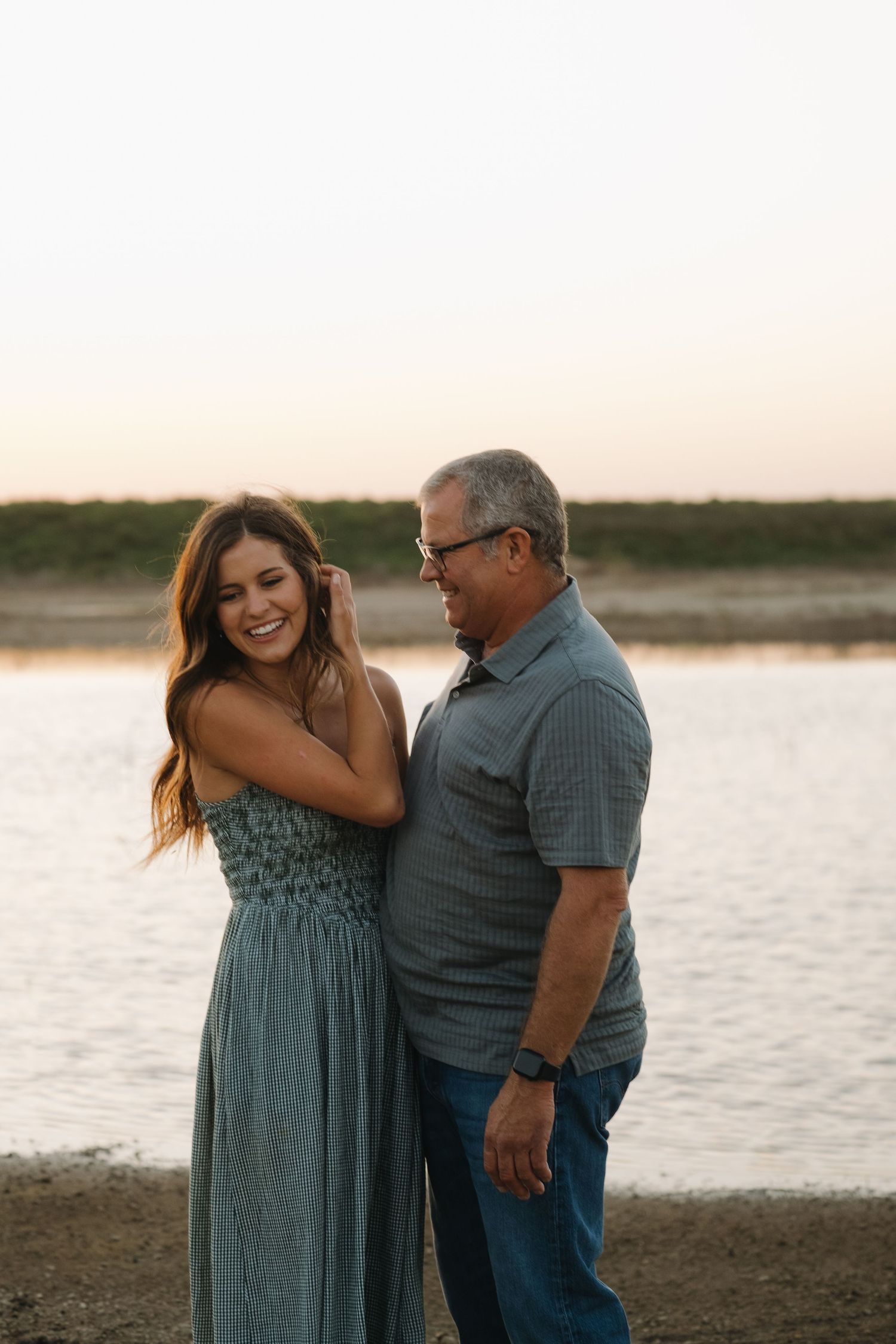 Couple embracing by the lake during sunset.