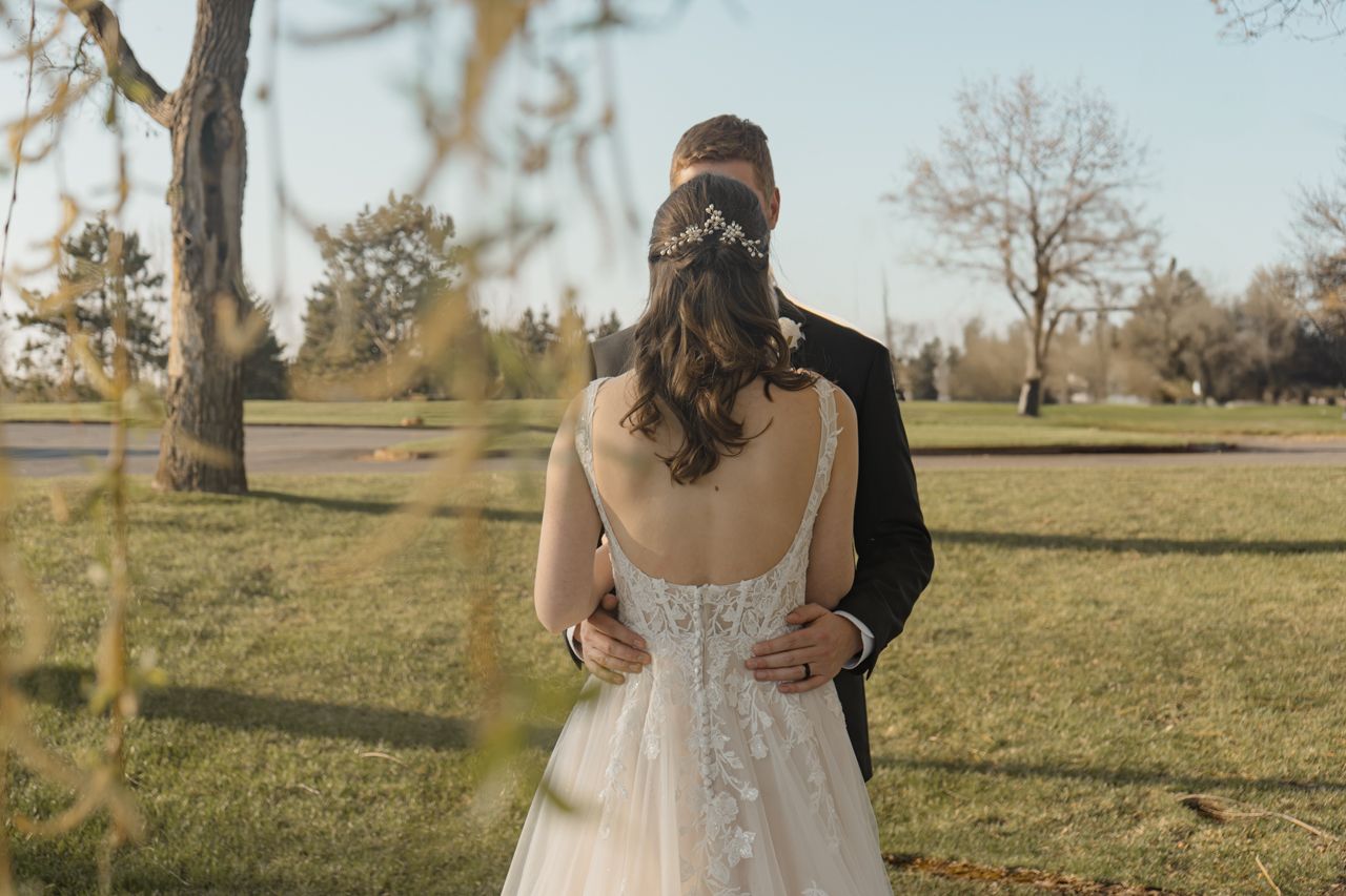 Couple embracing outdoors in a park setting during their wedding day.