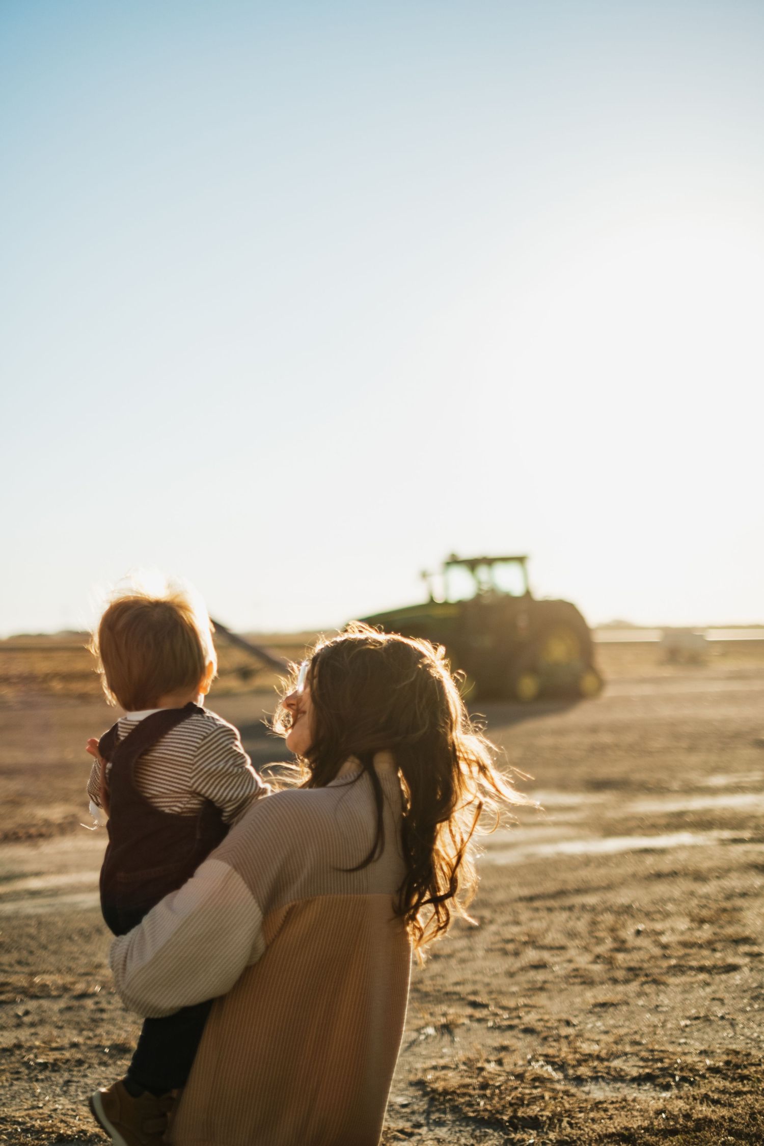 Silhouetted figures embracing during golden hour in an open field.