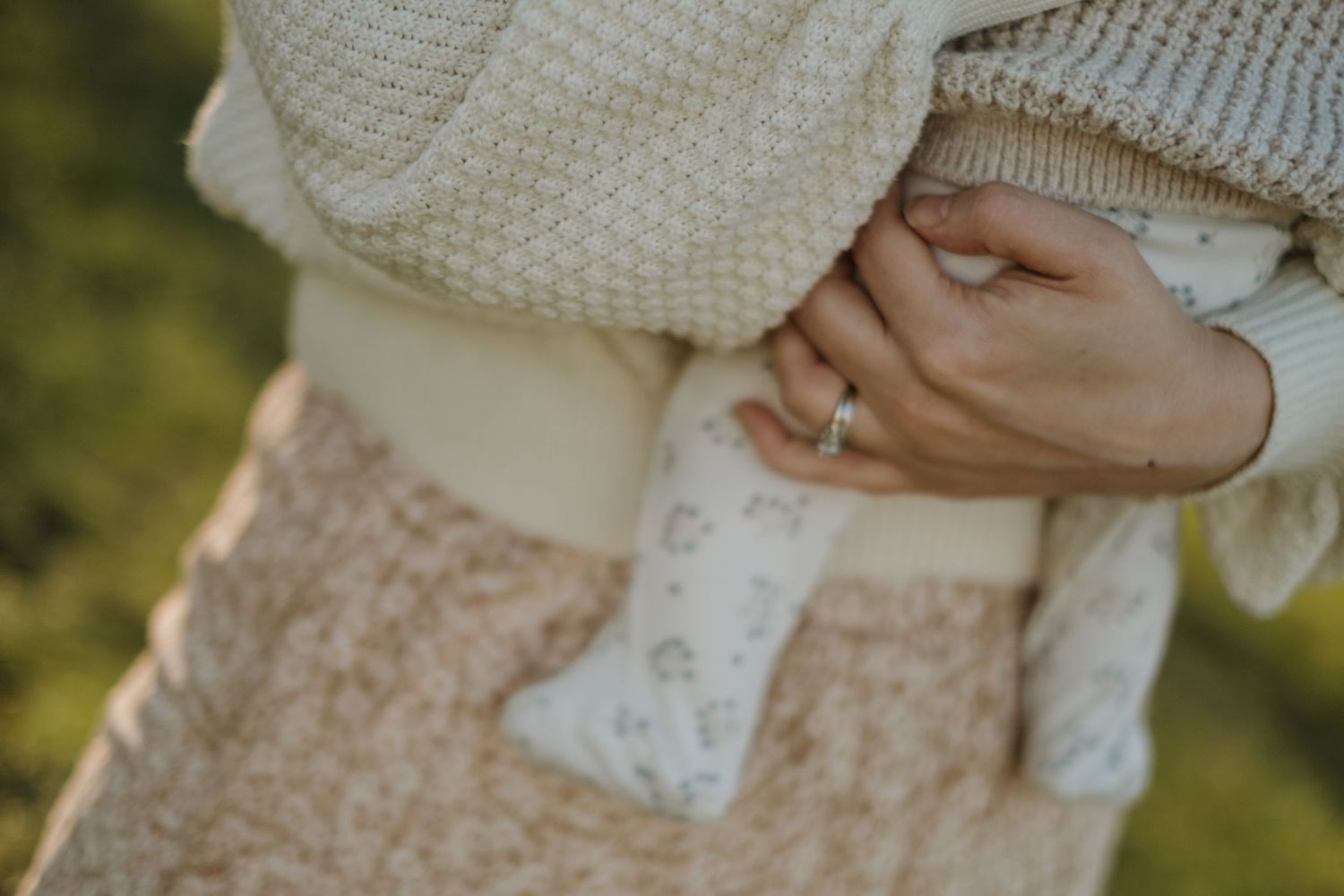 Detail shot of cream colored knit sweater and floral dress fabric.