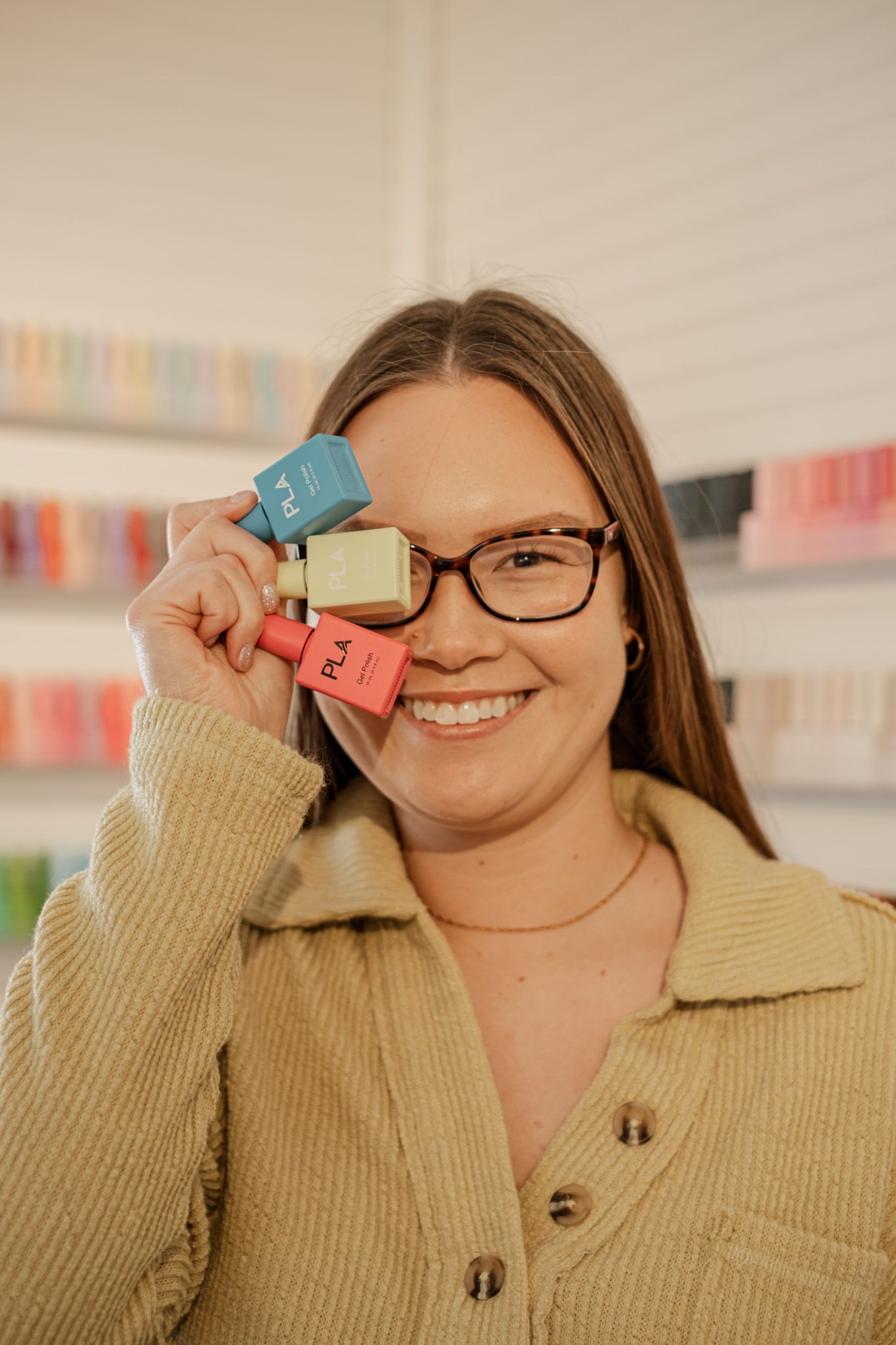 Person in beige sweater holding colorful sticky notes while smiling.
