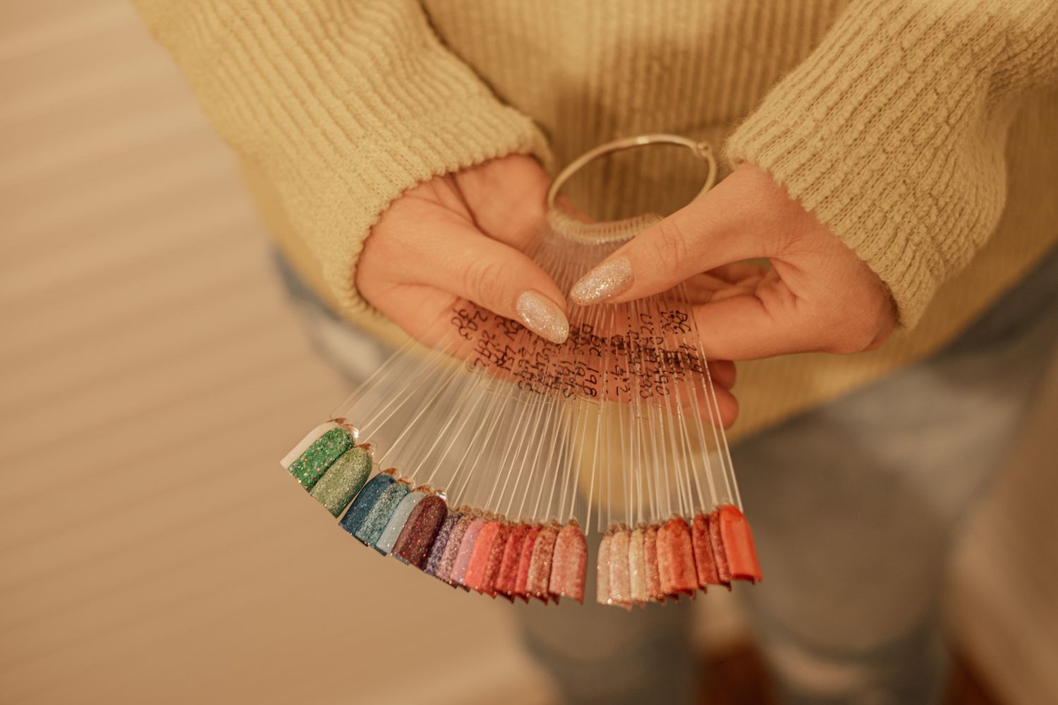Hands working with colorful nail polish bottles in professional setting.