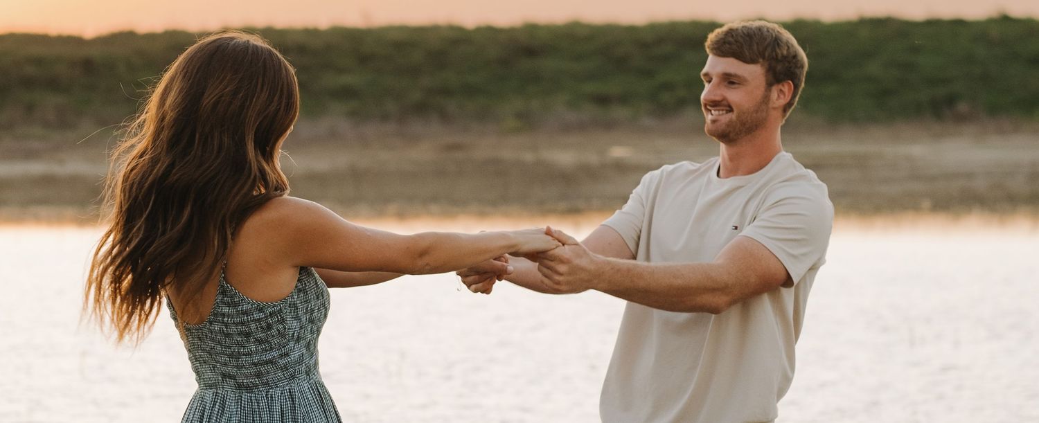 Couple shares intimate moment on sandy beach during golden hour.