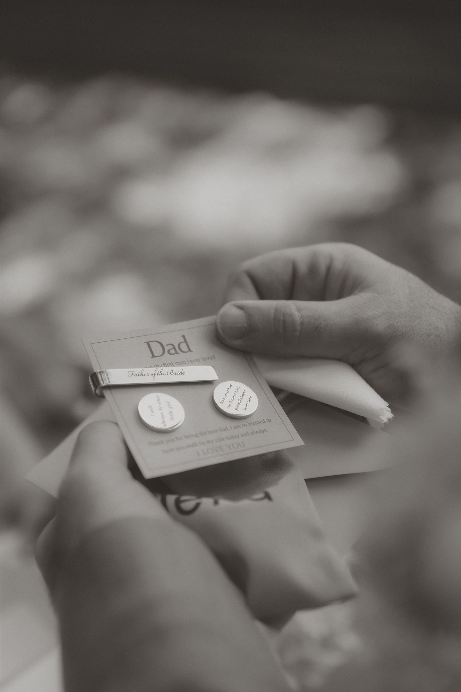 Hands holding monogrammed cufflinks on a Dad Father of the Bride card, a thoughtful wedding gift.