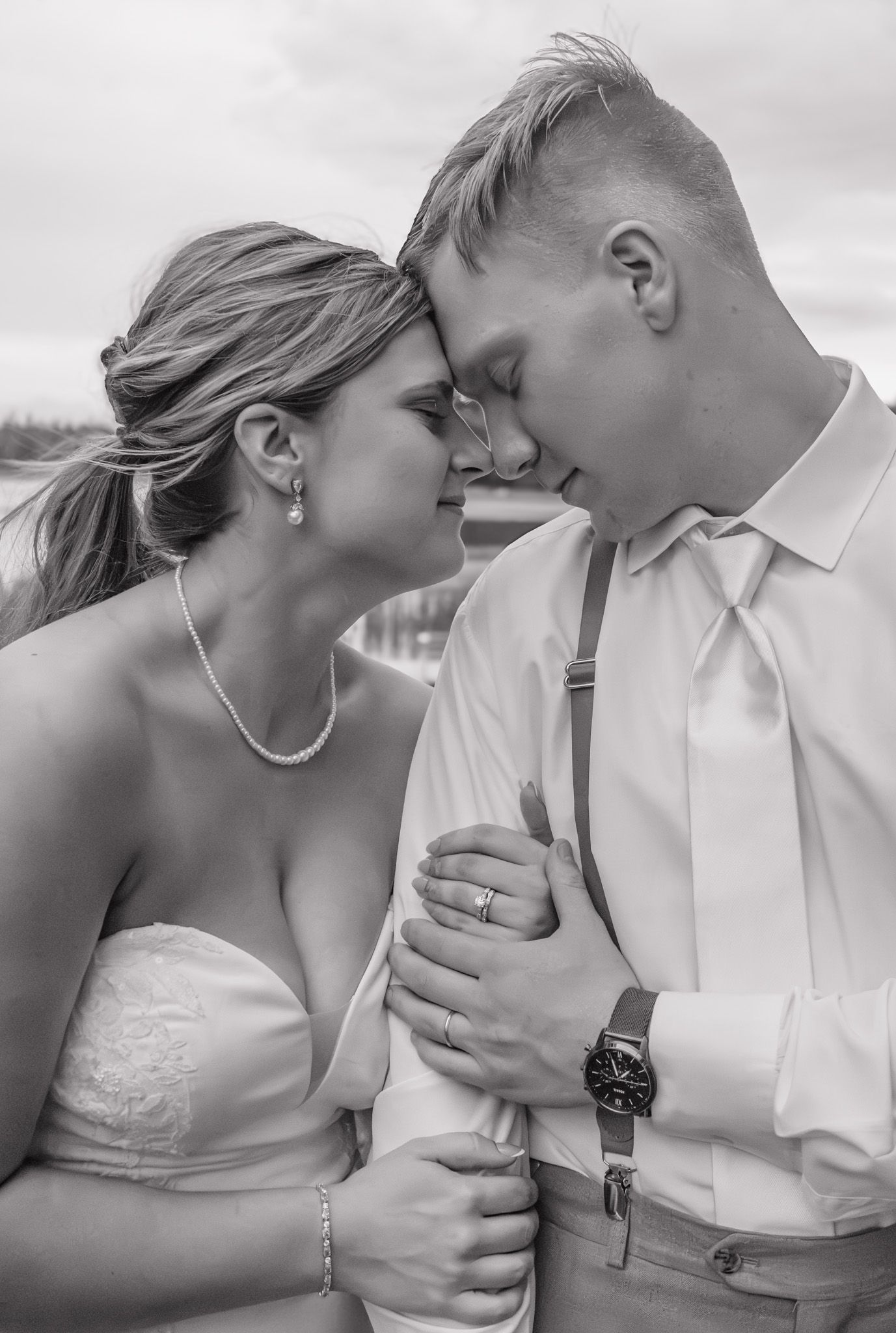 Bride and groom share a romantic forehead touch moment in black and white wedding portrait.