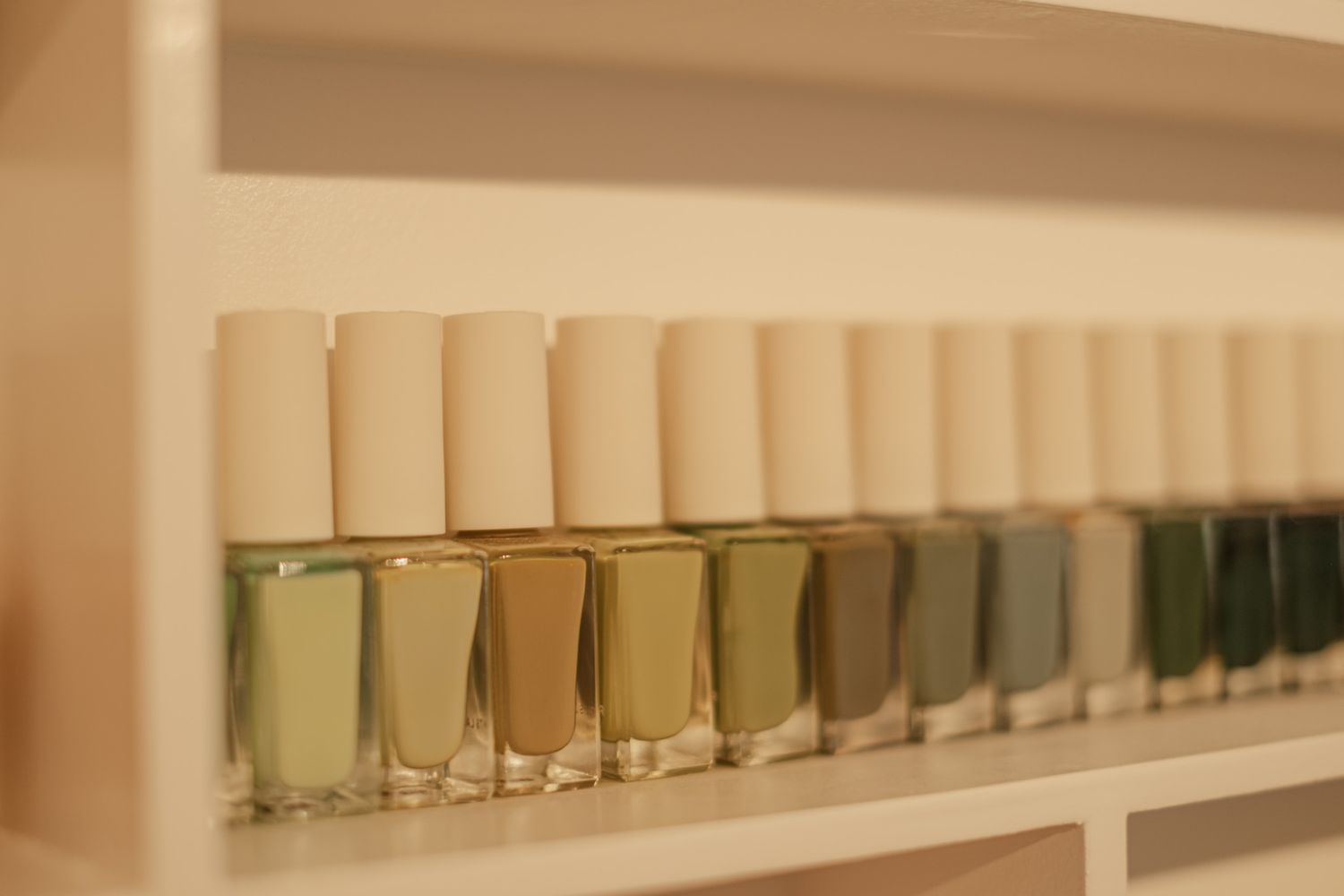 Collection of neutral and pastel nail polish bottles displayed on wall shelving.