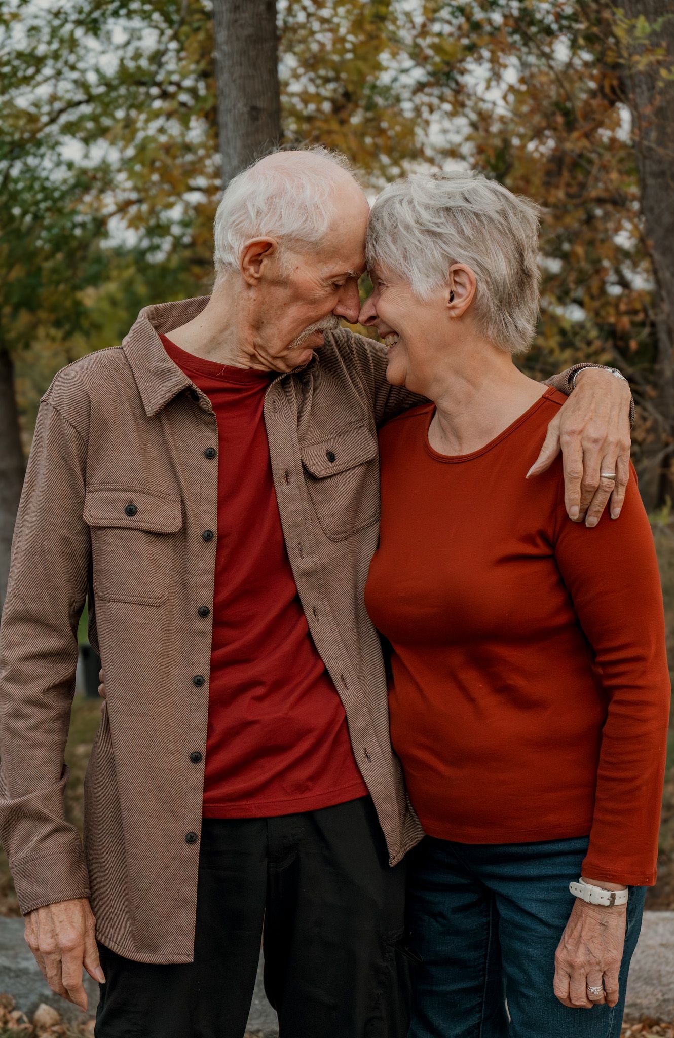 A tender moment captured in autumn between two people wearing coordinating red sweaters.