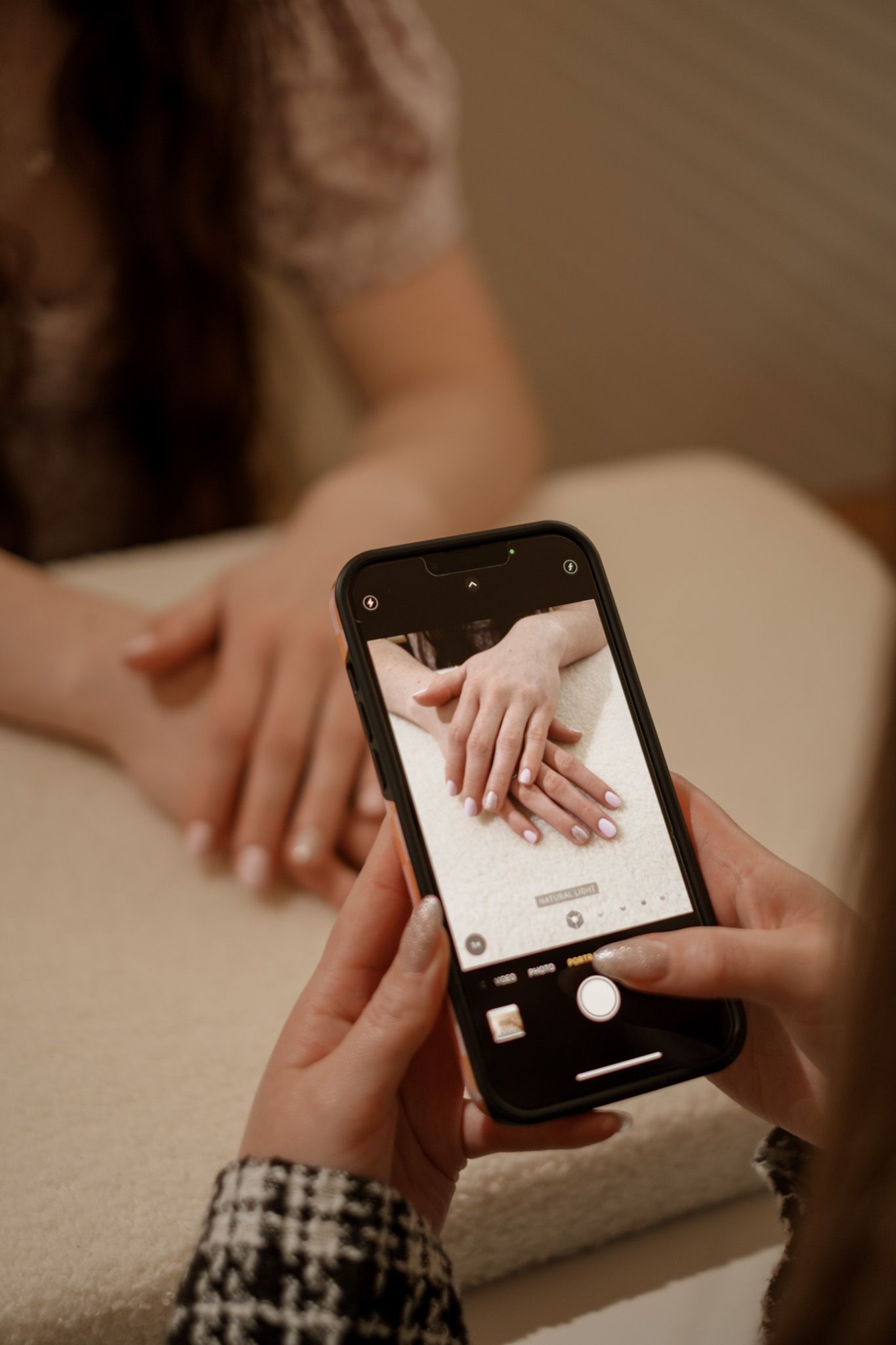 Hands holding smartphone to capture nail service process.