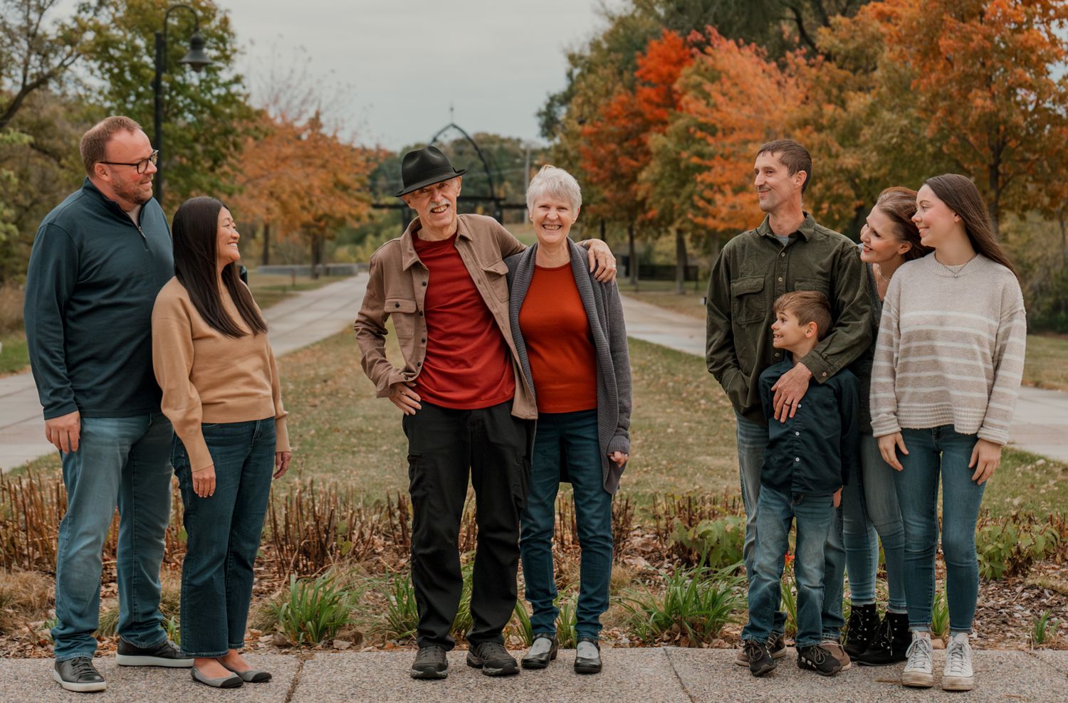 Group photo of people standing together outdoors during fall season with colorful foliage.