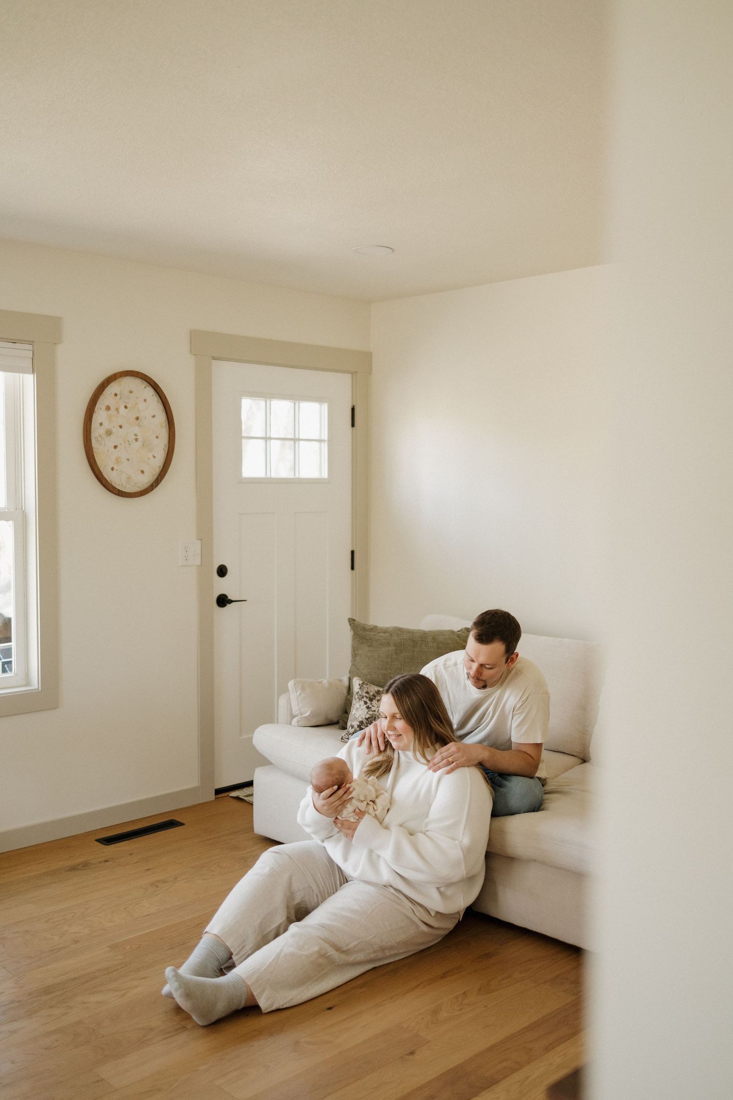 Young couple sitting on the floor of their cozy home, lovingly cradling their newborn baby together.