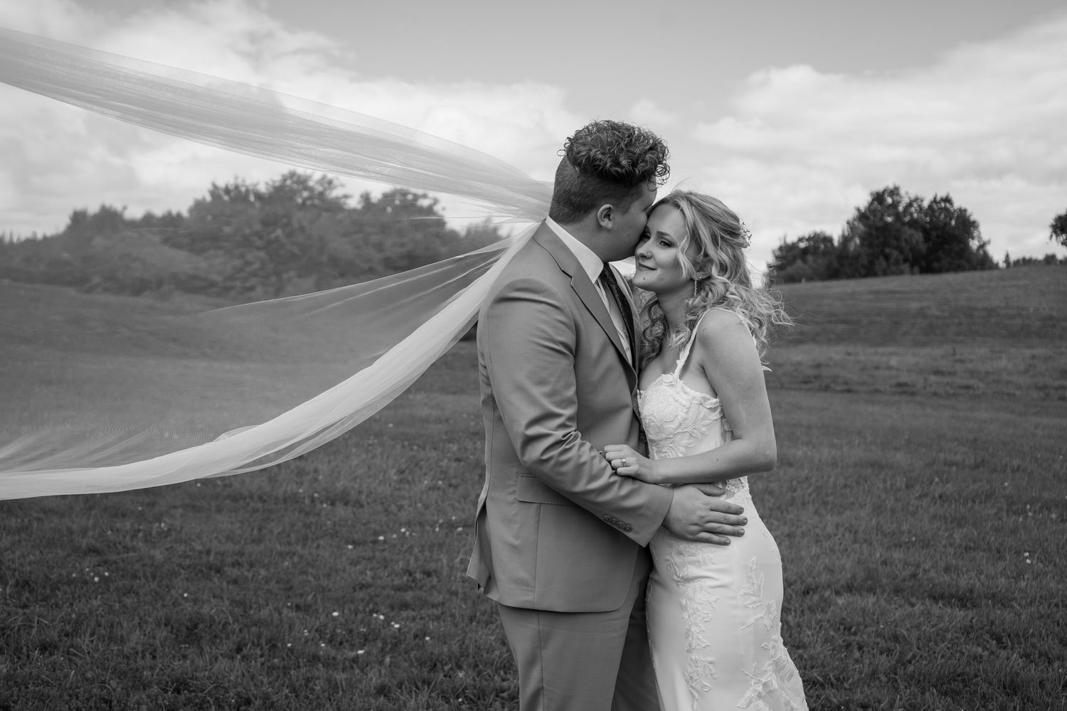 Black and white wedding photos capture intimate moments between newlyweds in an outdoor setting.