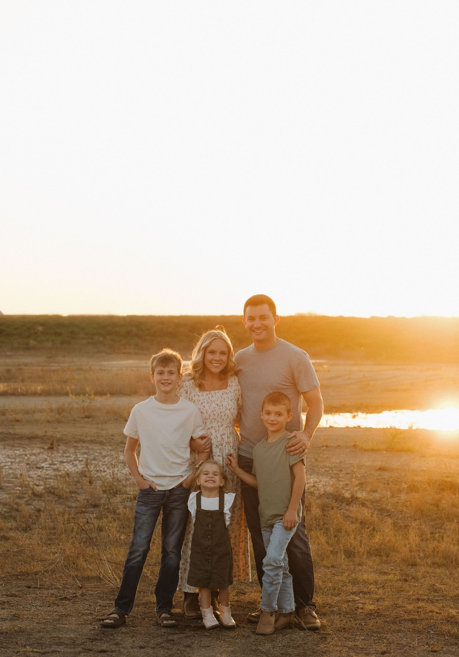 Family portrait at golden hour with a scenic lake backdrop.