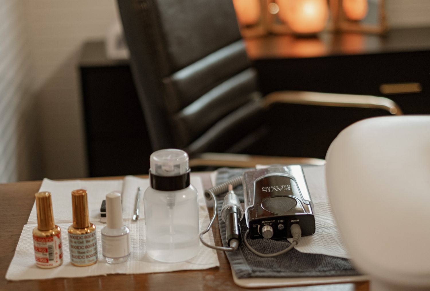 Nail polish bottles and manicure supplies arranged on wooden table with warm lighting.