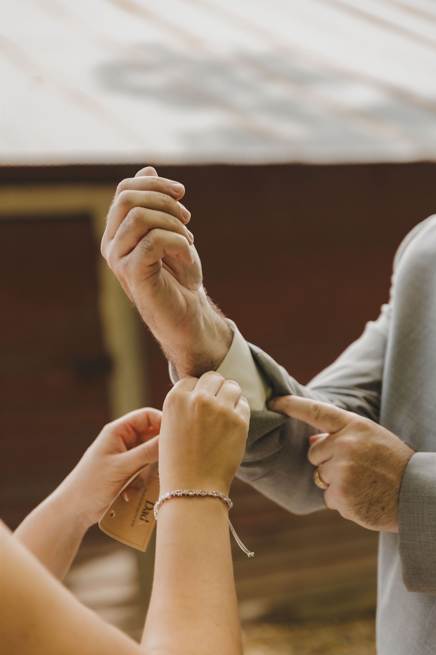 Hands adjusting a groom's suit cuff before the wedding ceremony.