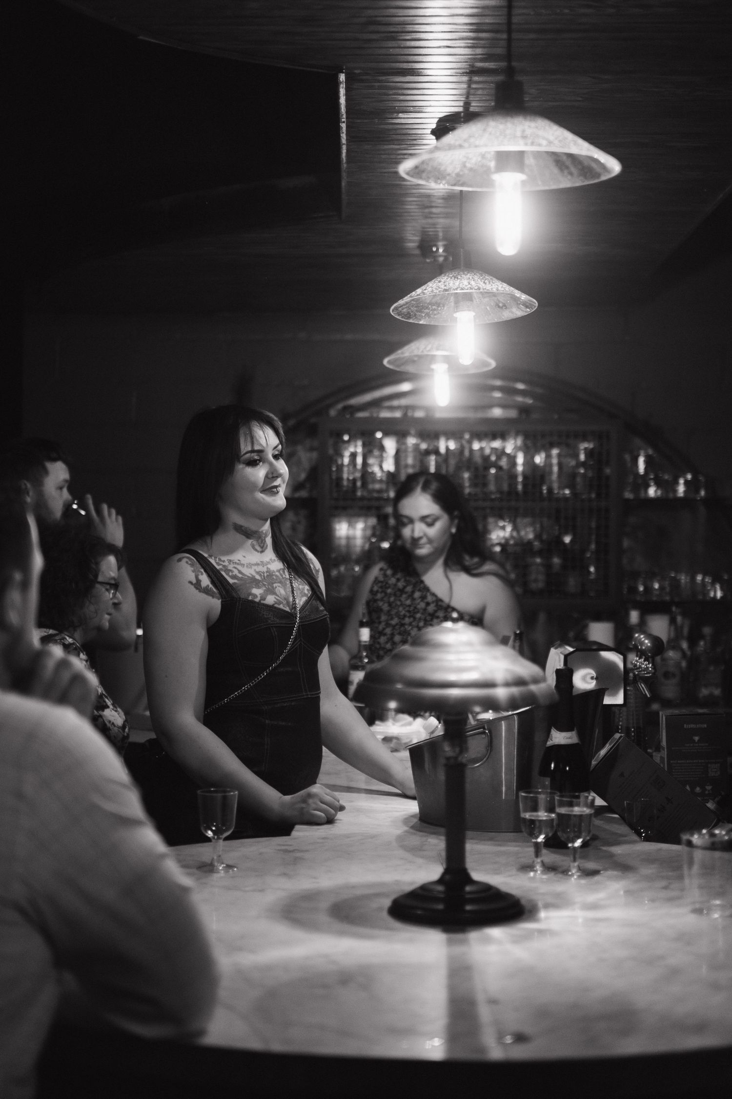Dimly lit bar scene with pendant lamps illuminating the counter.