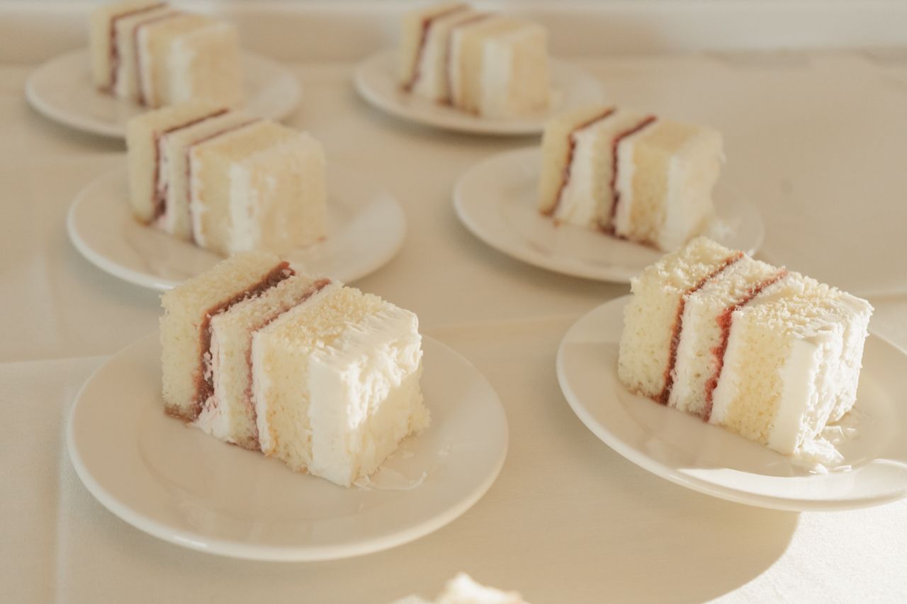 White layered tea sandwiches served on small plates at a wedding reception.
