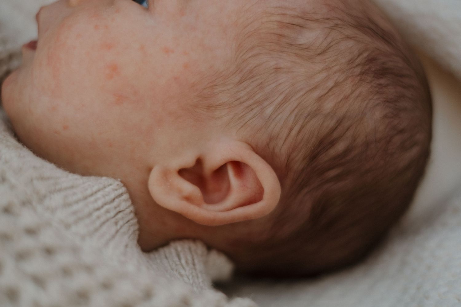 Close-up profile view of sleeping newborn's face and head.