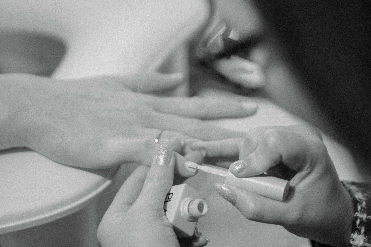 Black and white close-up photo of hands preparing food in a professional kitchen setting.