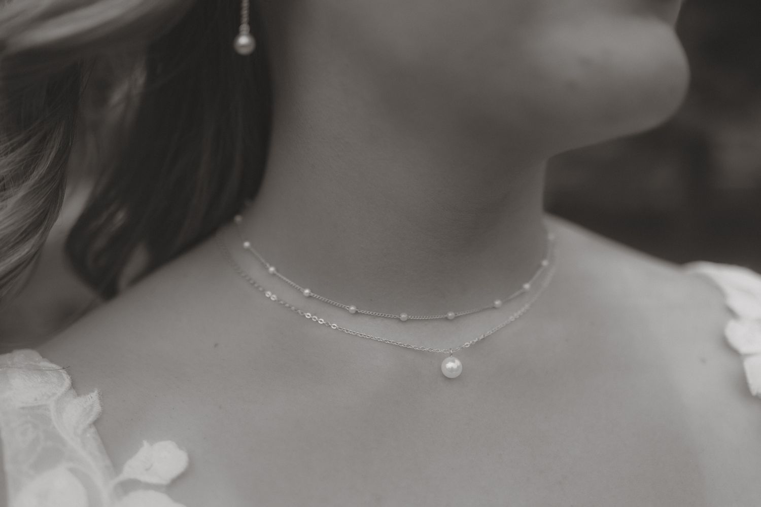 Close-up black and white photo of a bride wearing a delicate pearl choker necklace.