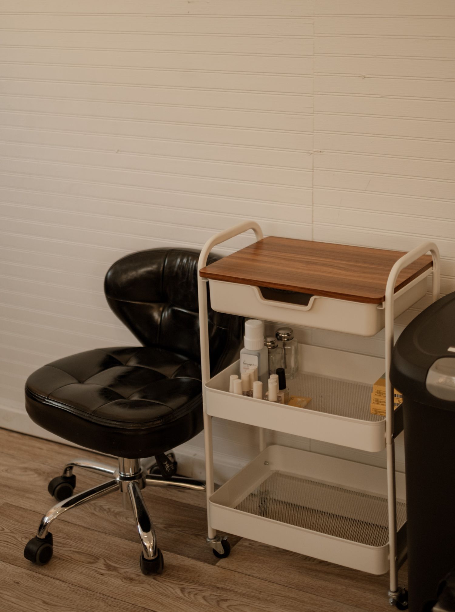 Modern office space with black leather chair and wooden desk against white walls.