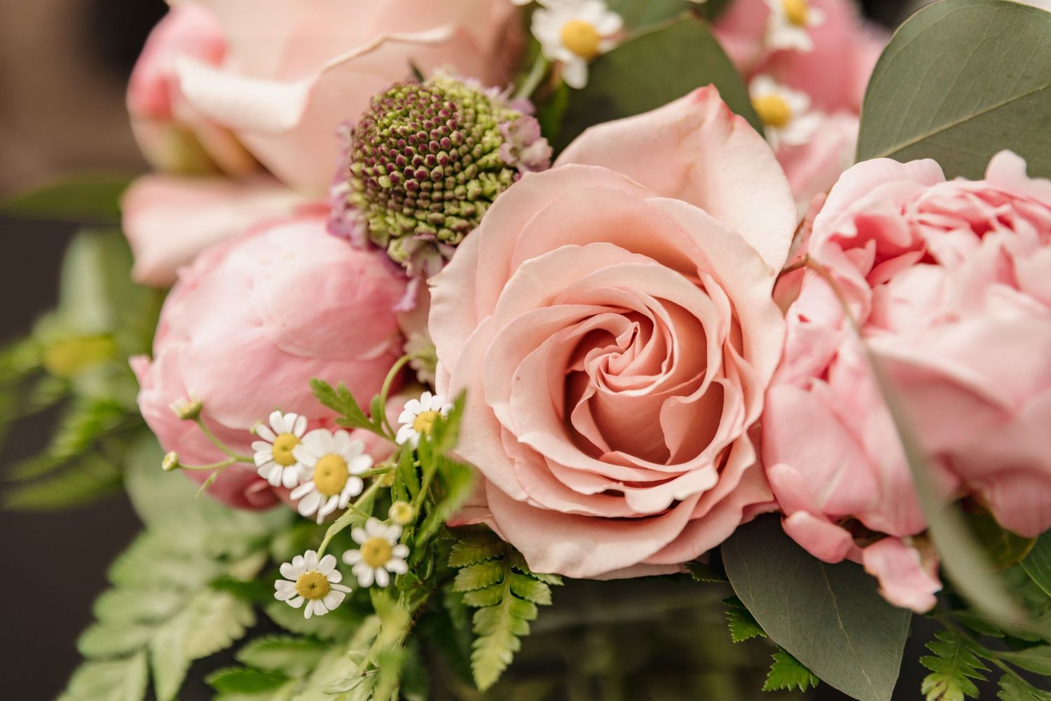 Close-up of a elegant pink rose bouquet with daisies and green foliage, perfect for weddings or romantic occasions.