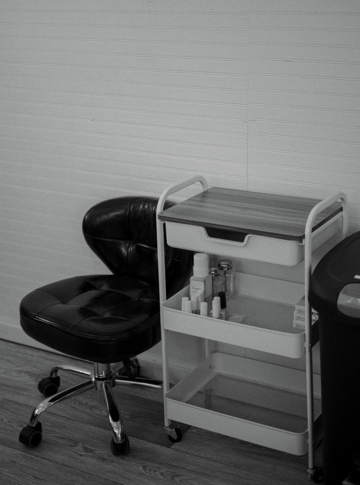 Grayscale image of an office setup with a black chair and minimalist desk.