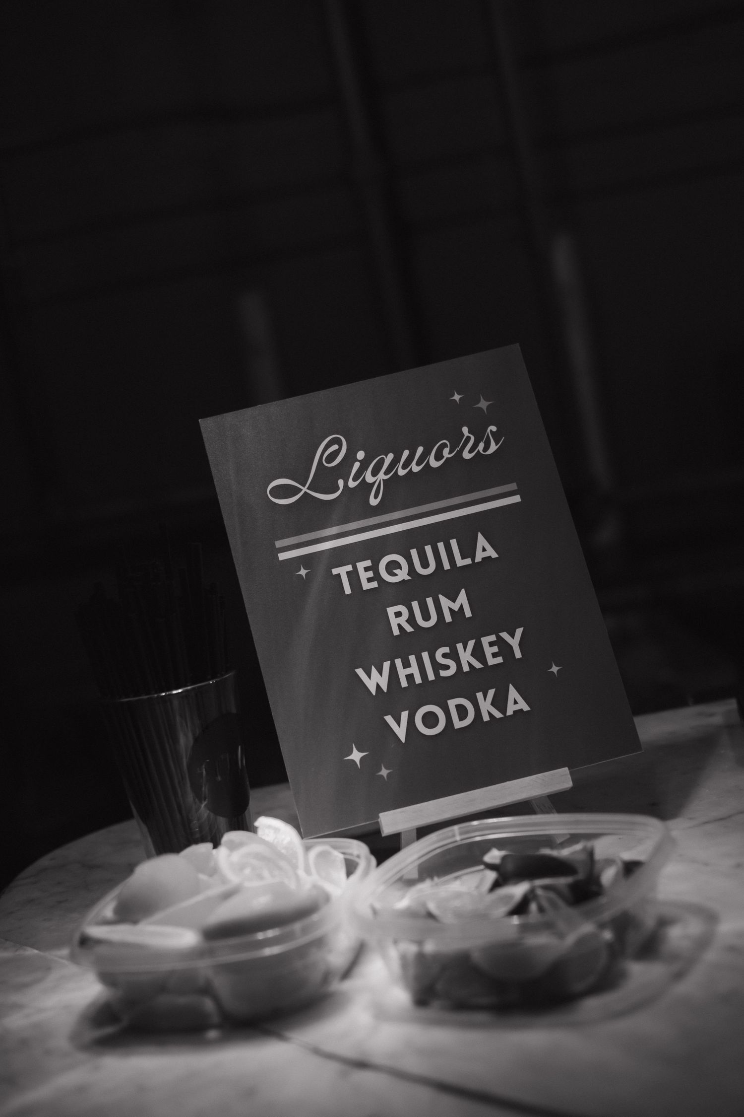 Black and white photo of liquor category signs including vodka, tequila, rum and whiskey.