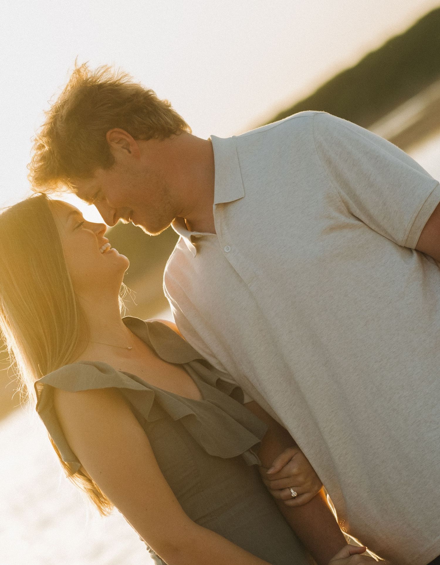Romantic couple silhouetted against golden sunset light in intimate embrace.
