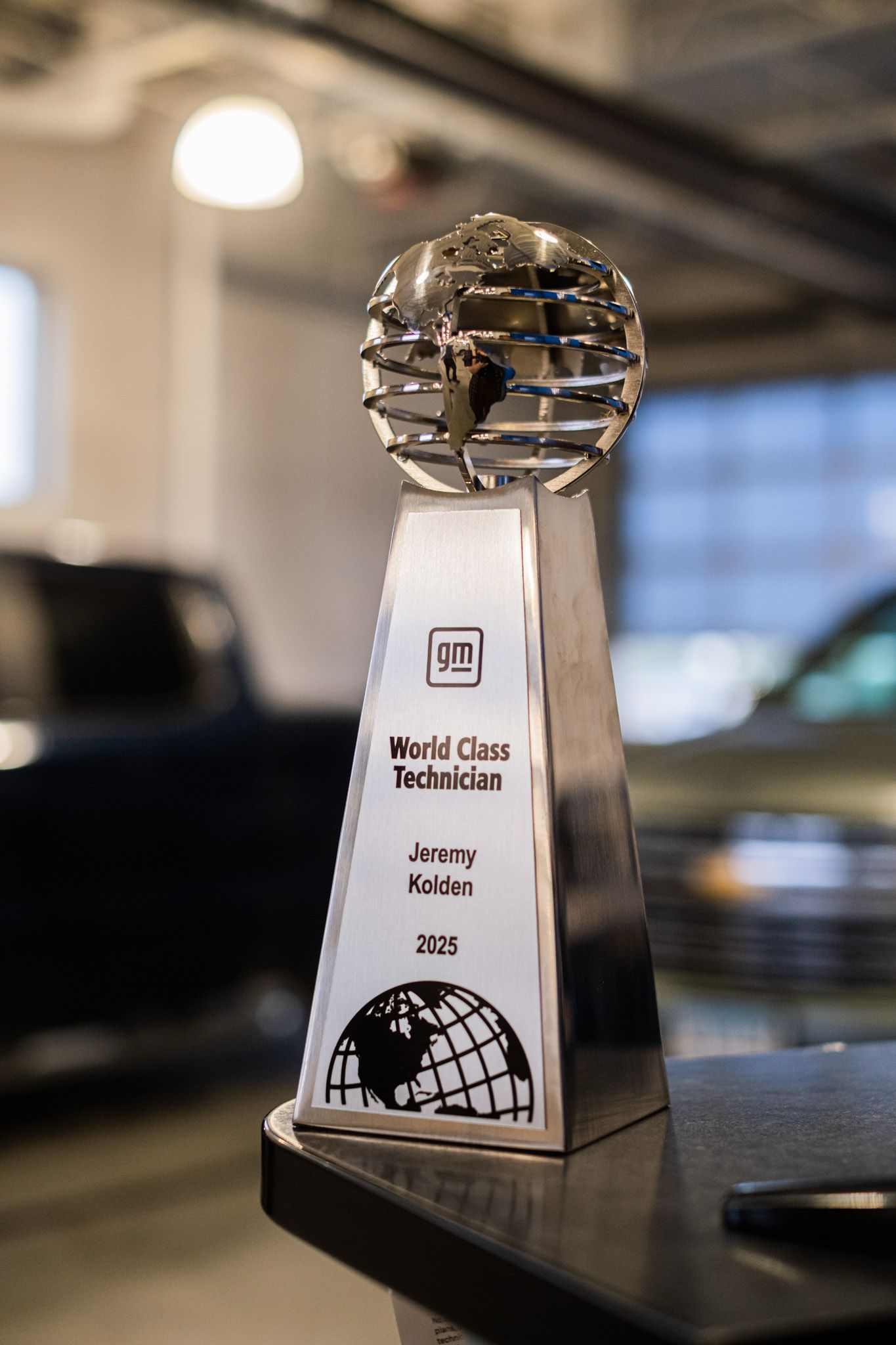 GM World Class Technician award trophy displayed on black surface with metallic globe design.