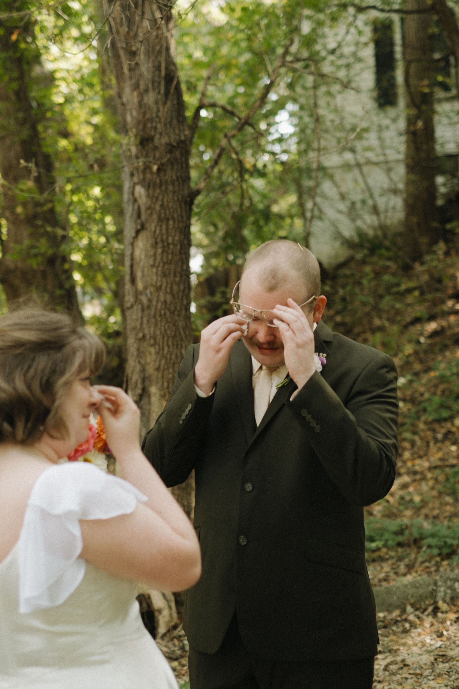 A touching first look moment between wedding couple in a wooded setting.