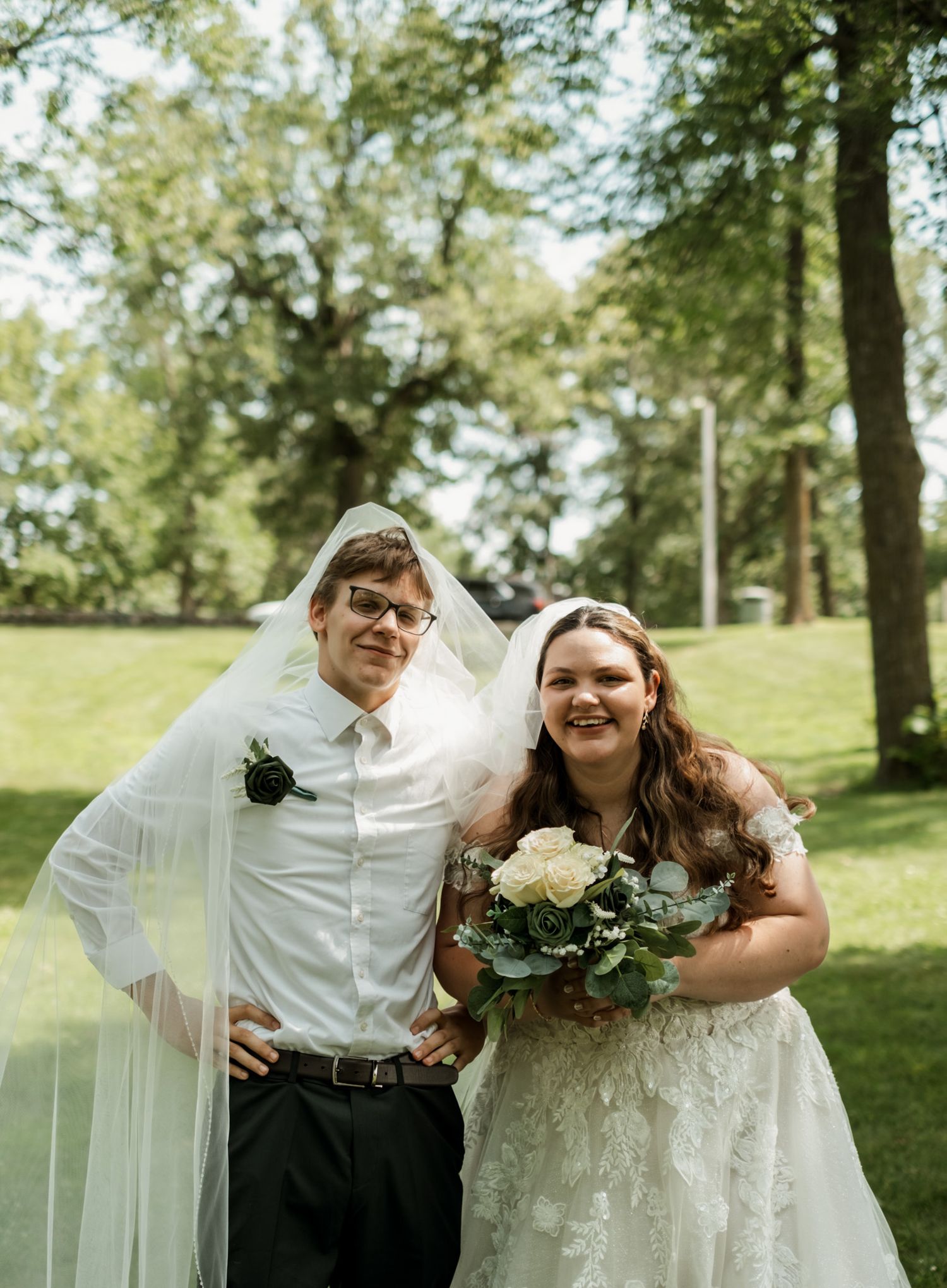 A newlywed couple poses together outdoors on their wedding day.