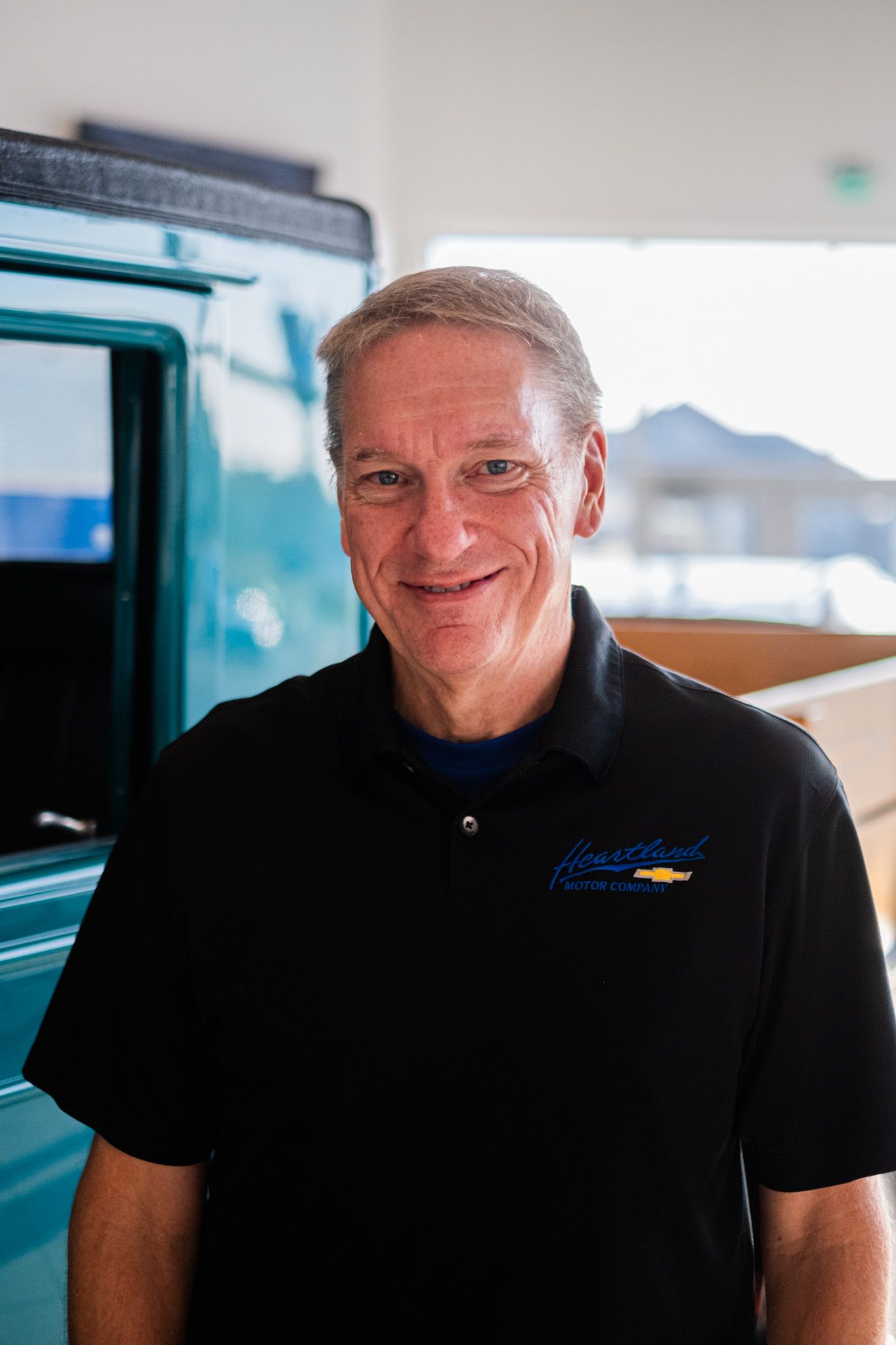 Staff member in black Chevrolet polo shirt smiling warmly at camera.