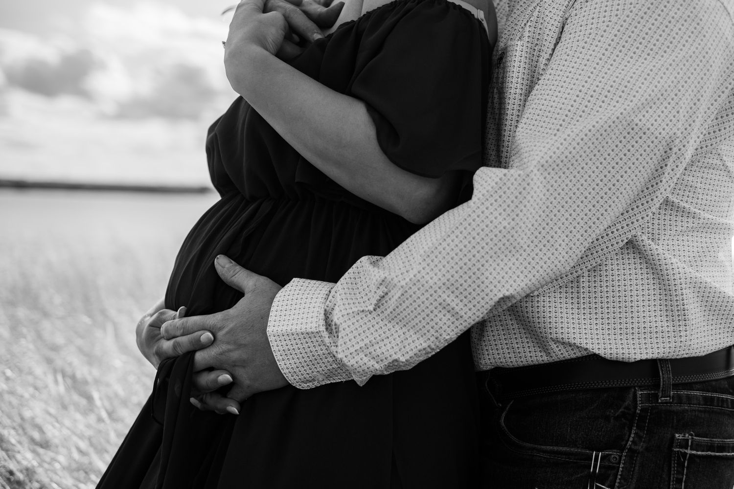 Black and white intimate portrait of couple embracing in rural setting.