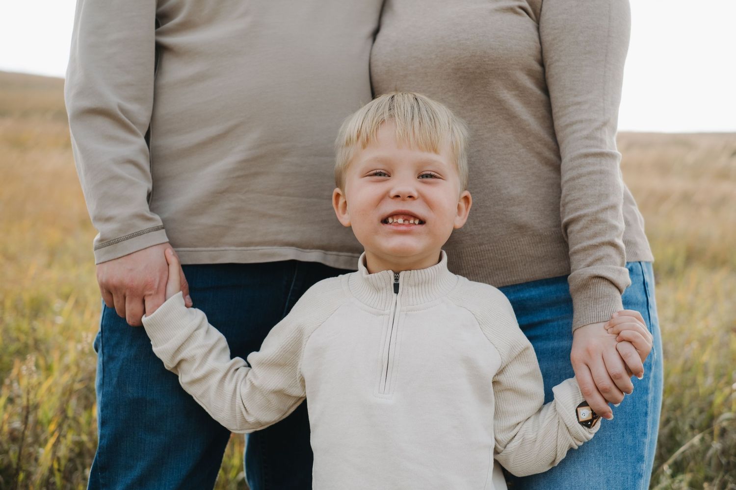 A family shares joyful expressions while standing in tall grass.