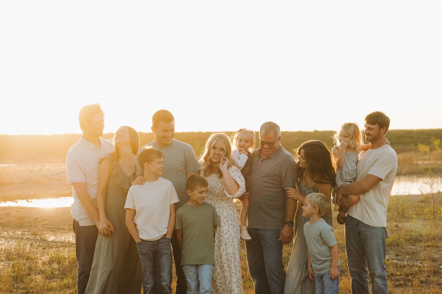 Family group photo silhouettes against a golden sunset on a grassy field.
