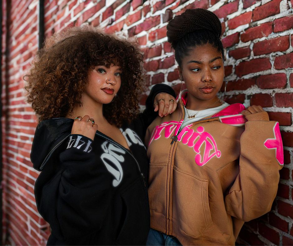 Two beautiful young ladies on a brick background, modeling clothing