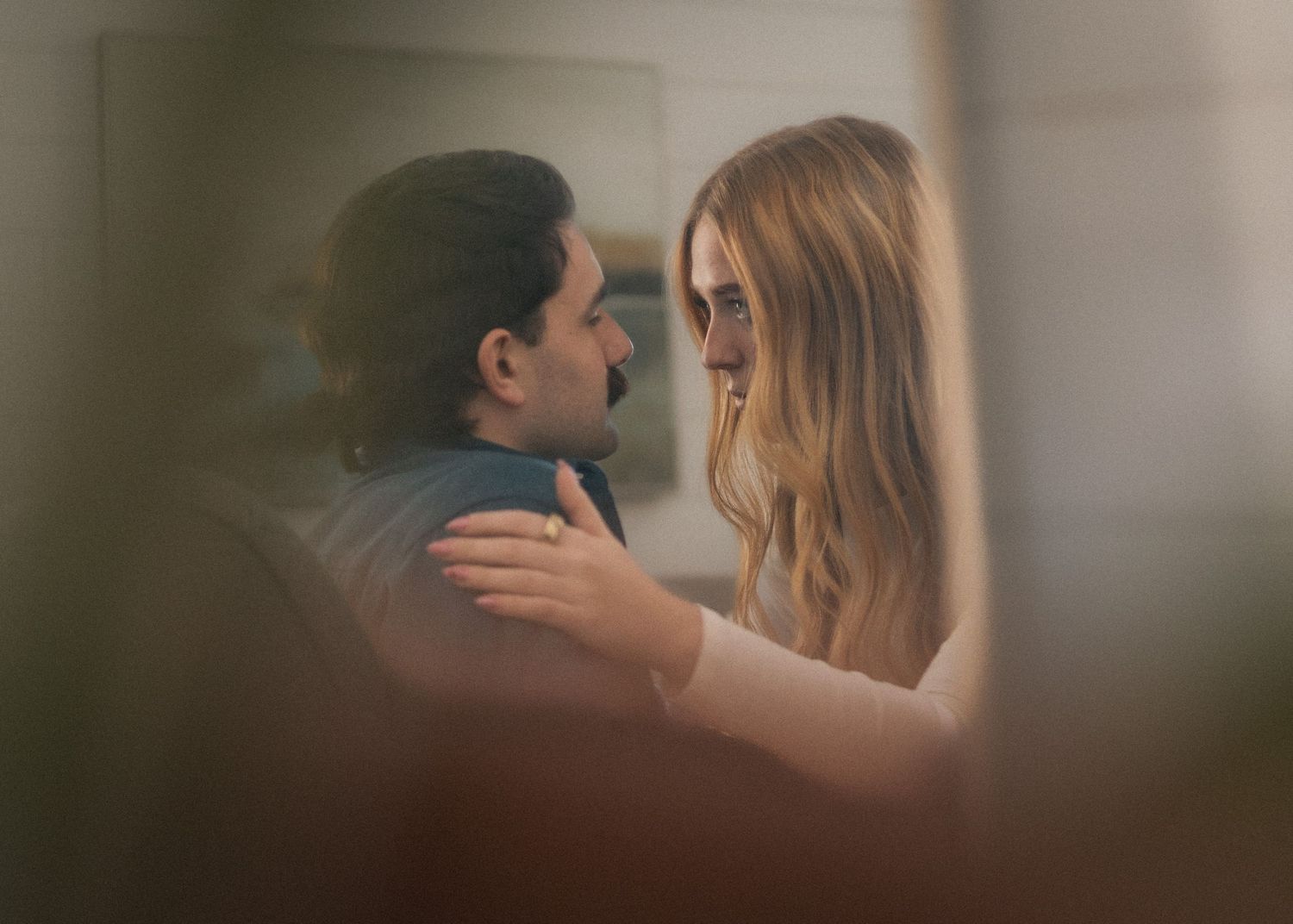 A couple shares an intimate moment, gazing into each other's eyes in a softly lit, romantic setting.