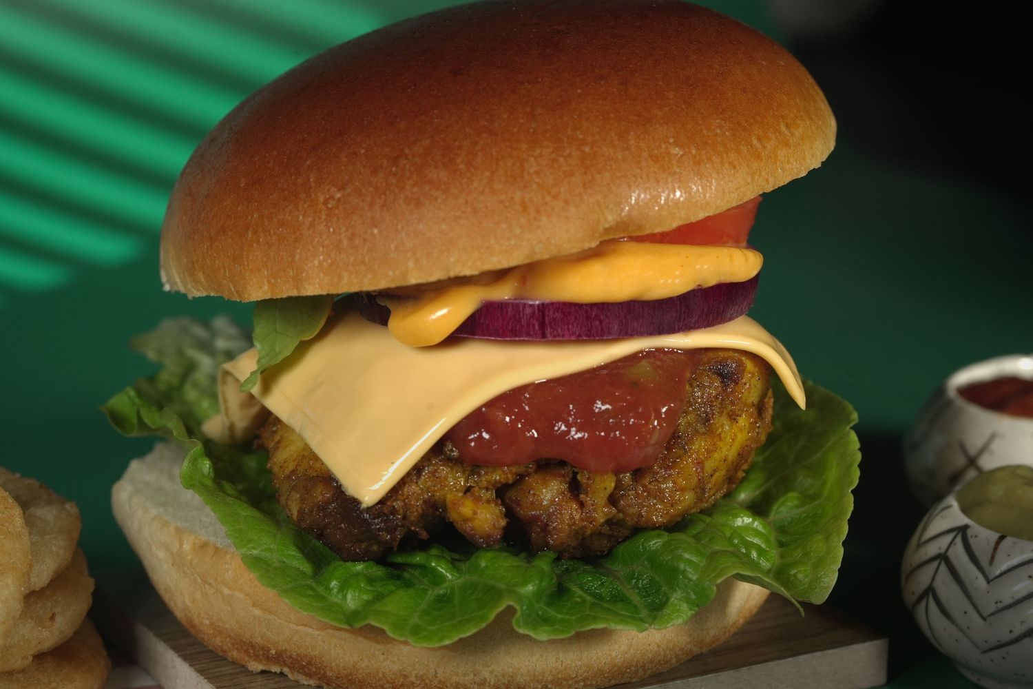 Juicy cheeseburger with lettuce, tomato and cheese on a brioche bun in dramatic lighting.