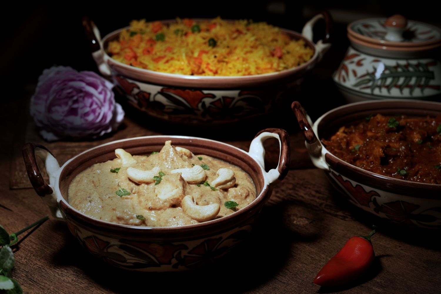 Traditional Indian curry dishes with rice and garnishes in copper serving bowls.