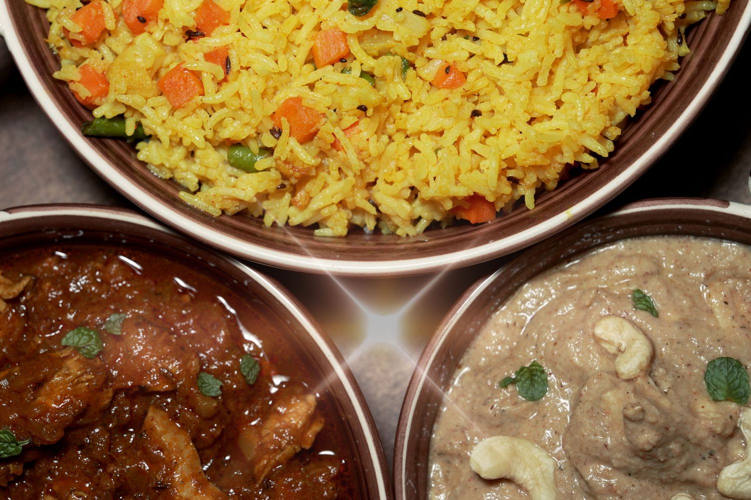 Yellow rice and curry dishes served in metal bowls with garnish.