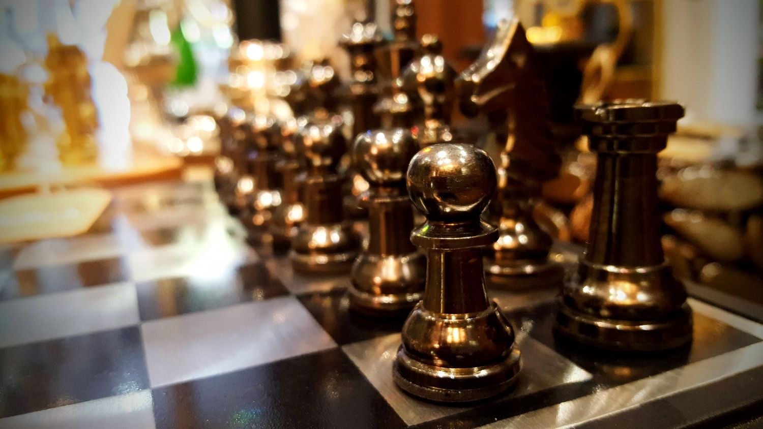 Vintage brass chess pieces arranged on display in warm lighting.