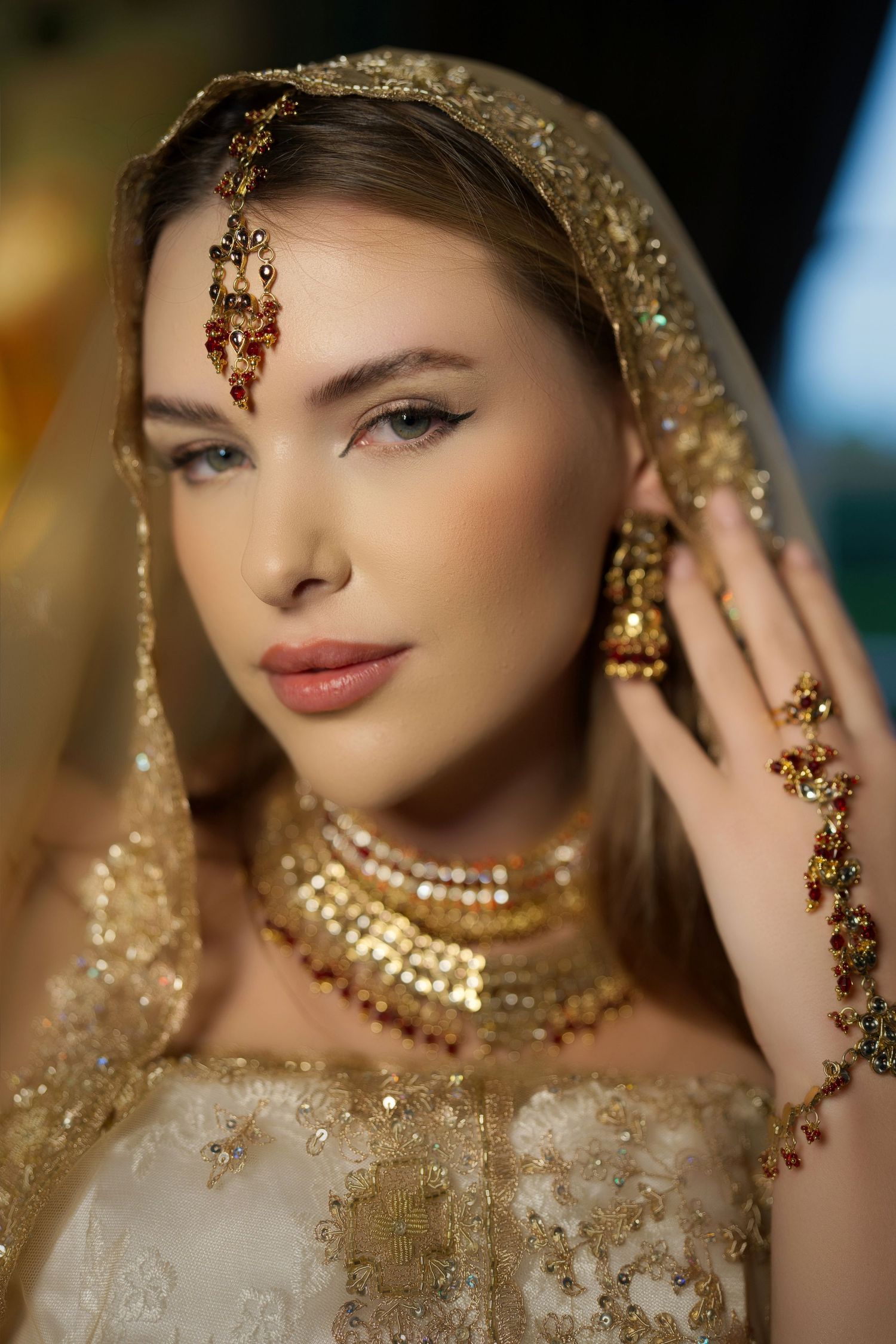 South Asian bridal fashion with gold jewelry and embellished veil in warm lighting.