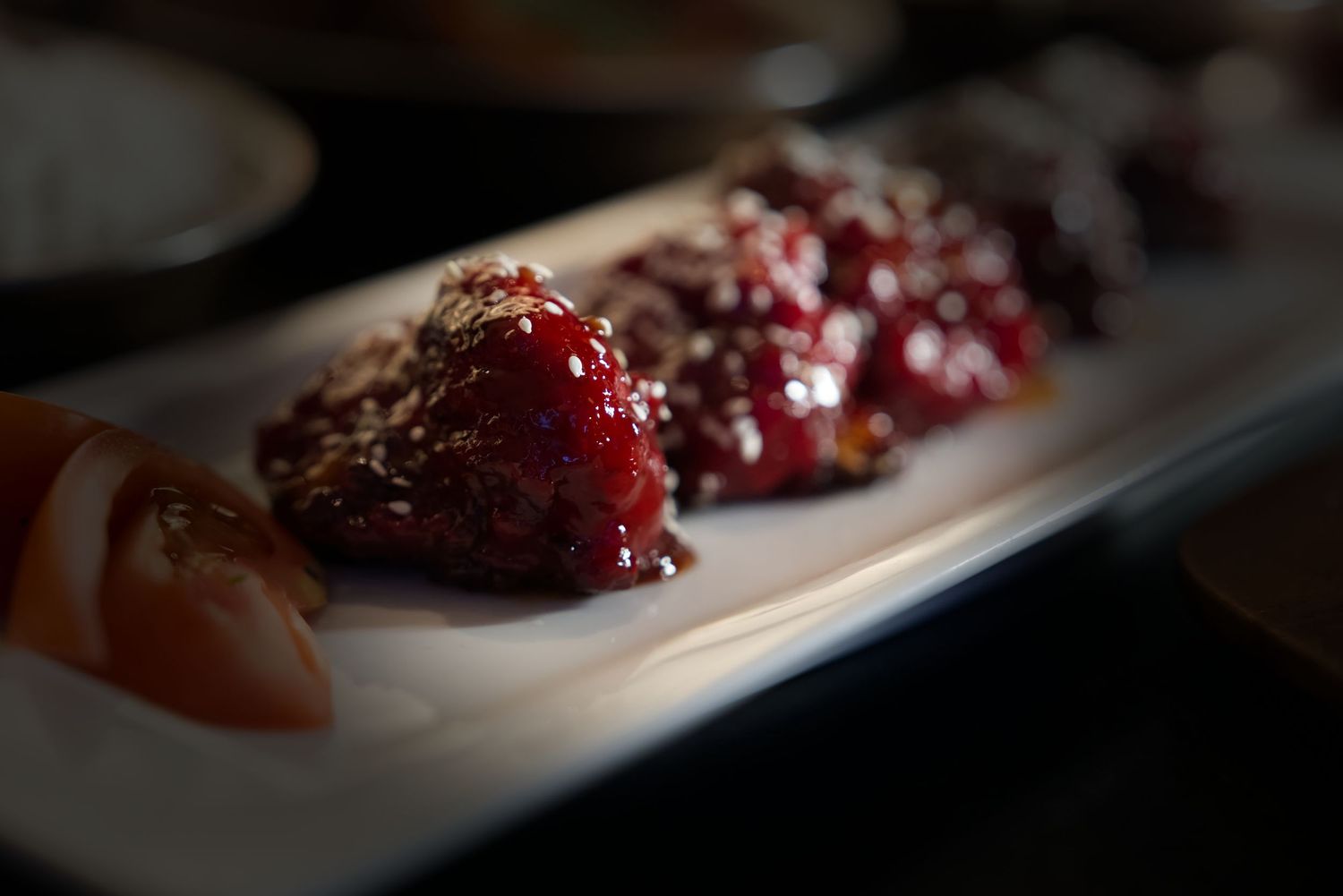 A close-up view of cranberry sauce dripping over the edge of a white serving plate.