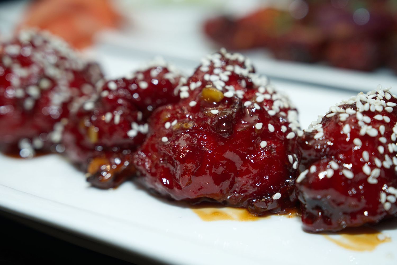 Glazed chicken wings drizzled with sweet and sticky sauce on a white serving plate.