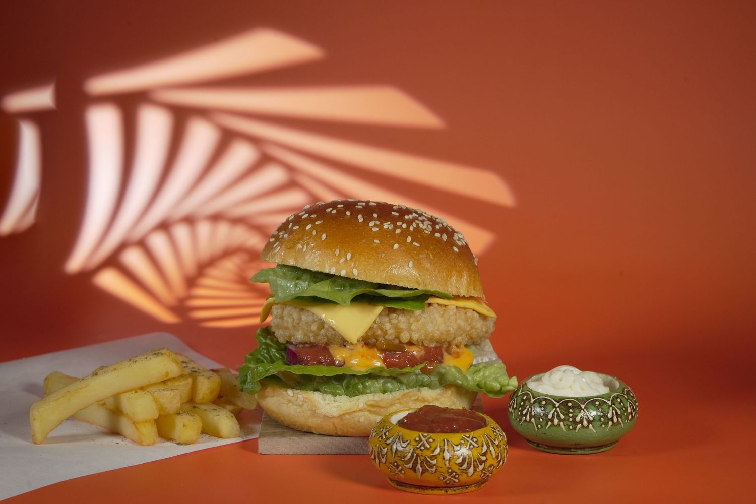 Artisanal burgers with sesame buns and fries arranged under dramatic lighting.