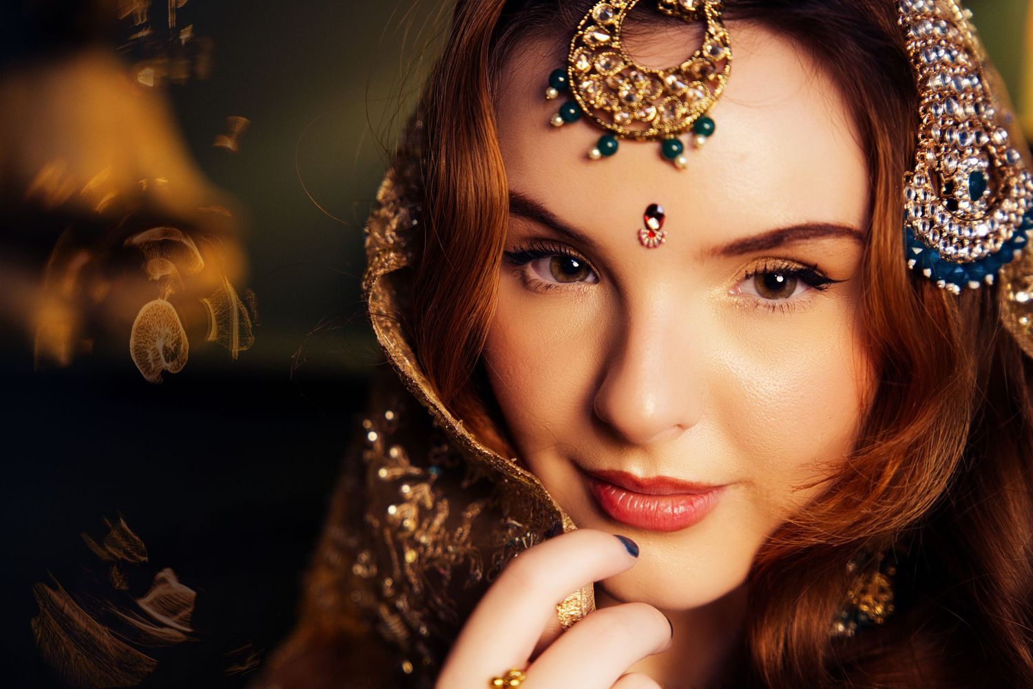 Close-up portrait with ornate gold jewelry and traditional Indian bridal accessories.