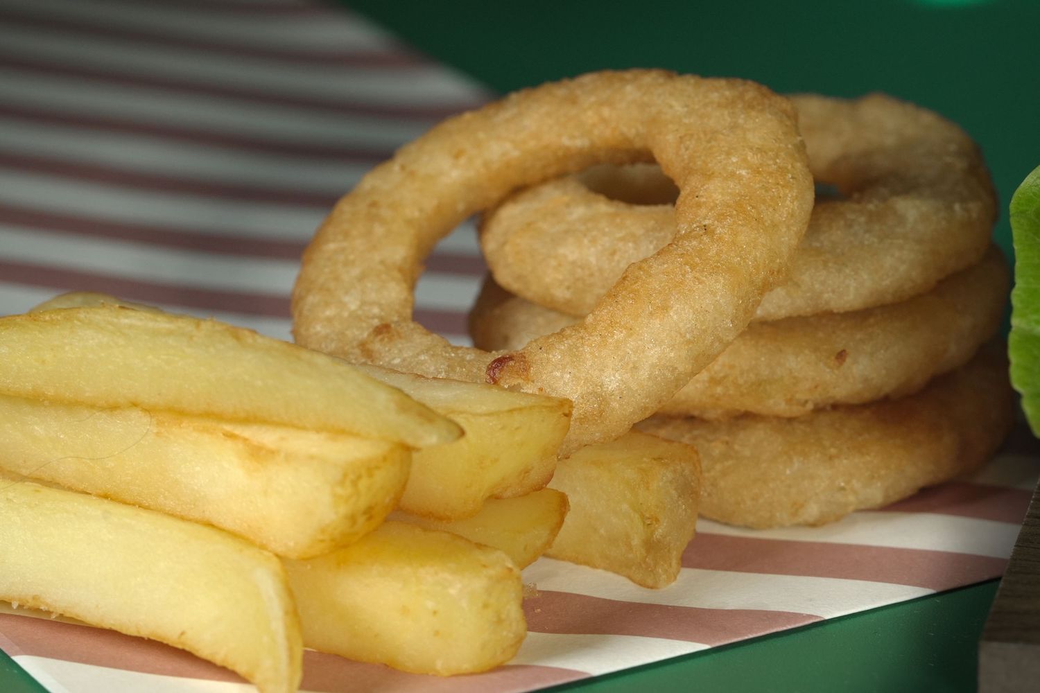 Golden crispy onion rings and french fries arranged on a white surface.