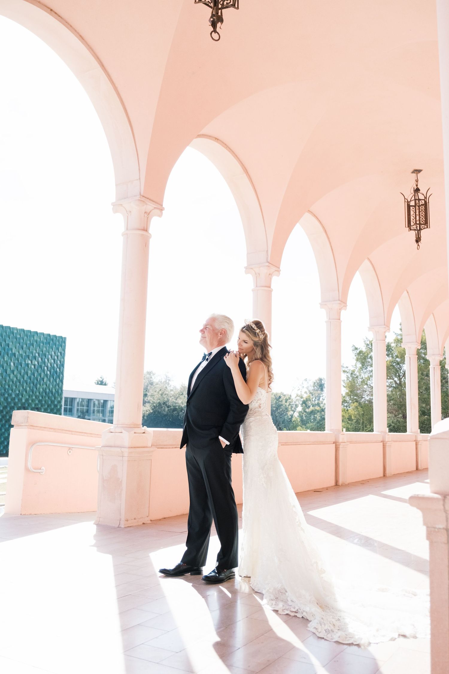 A wedding couple poses on an elegant white stone staircase with ornate balustrades at a historic venue. UK wedding photographer.