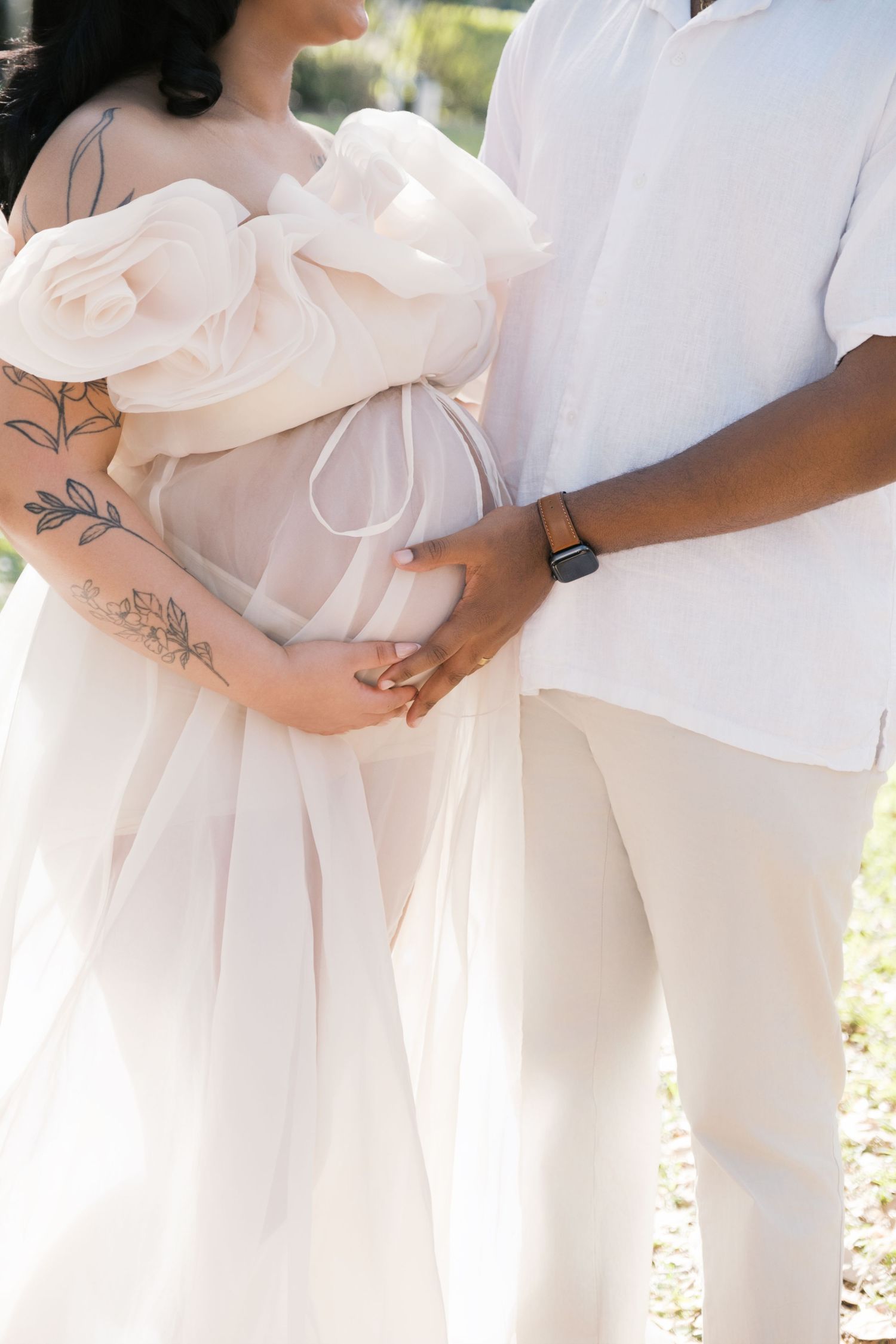 a maternity session in white dresses holding pink bouquets stand together at a garden, maternity london uk photographer.